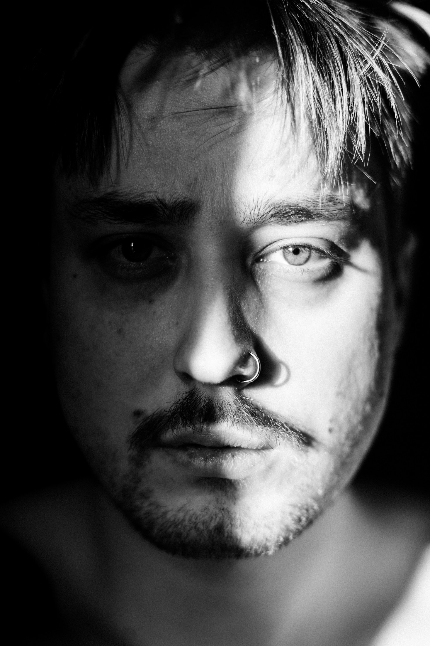 Close monochrome portrait with one eye illuminated by hard light.