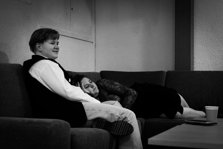 Two people rest together on a sofa in a quiet monochrome moment.